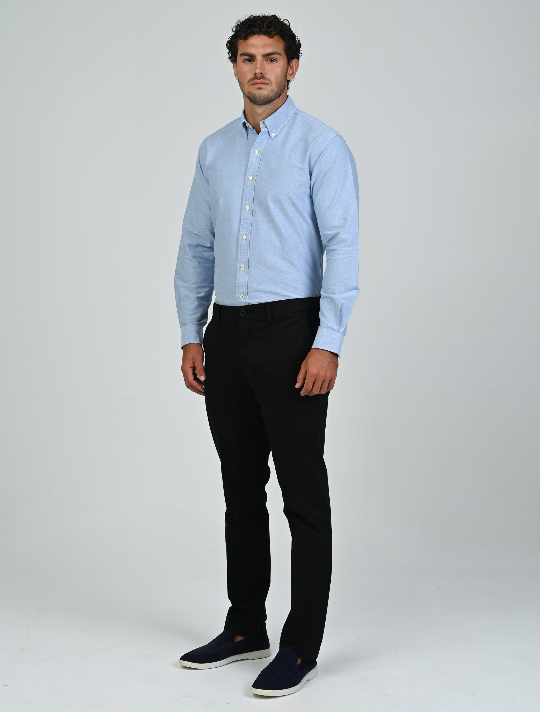 Model wearing the Marshall Menswear Harrington Oxford Shirt in tropical blue with tailored navy trousers and white sneakers for a smart business casual look.