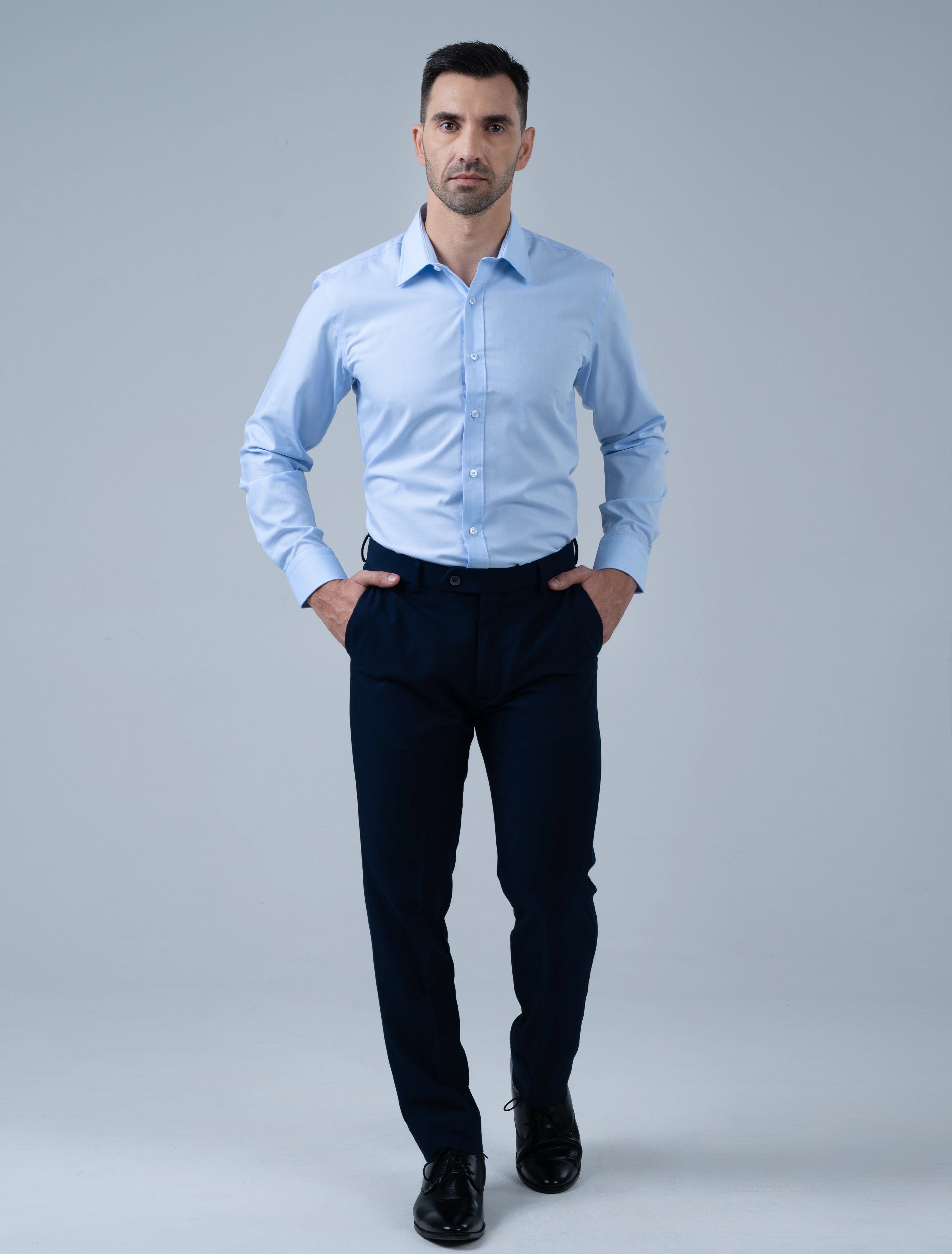 Full-length view of the Marshall Menswear Kingsley light blue men's dress shirt styled with navy trousers and black dress shoes for modern office wear and a professional look.