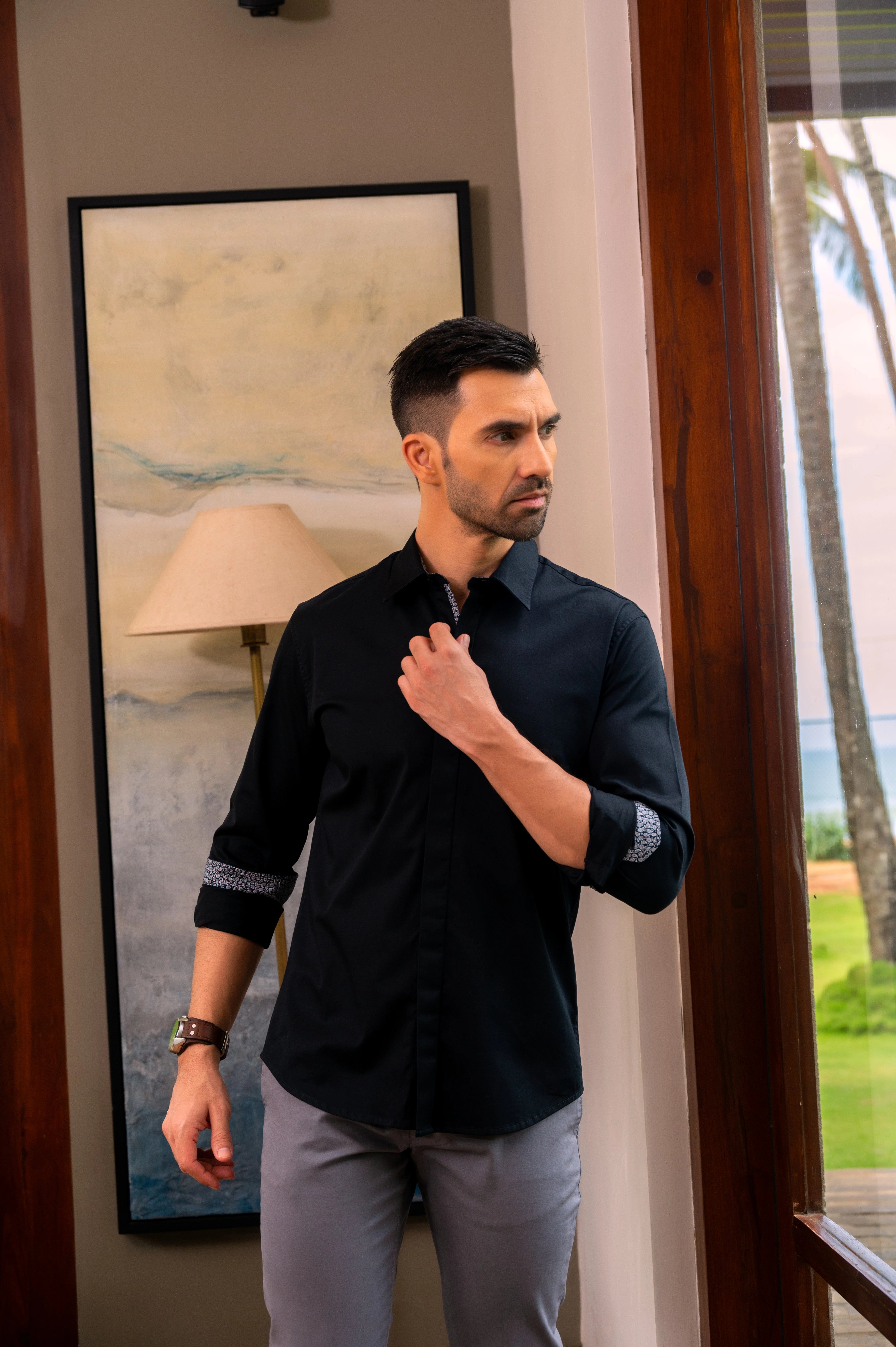Model wearing the Marshall Menswear Mystère Black men's premium cotton 4-way stretch casual shirt styled with grey  stone trousers and brown suede loafers for a polished casual look.