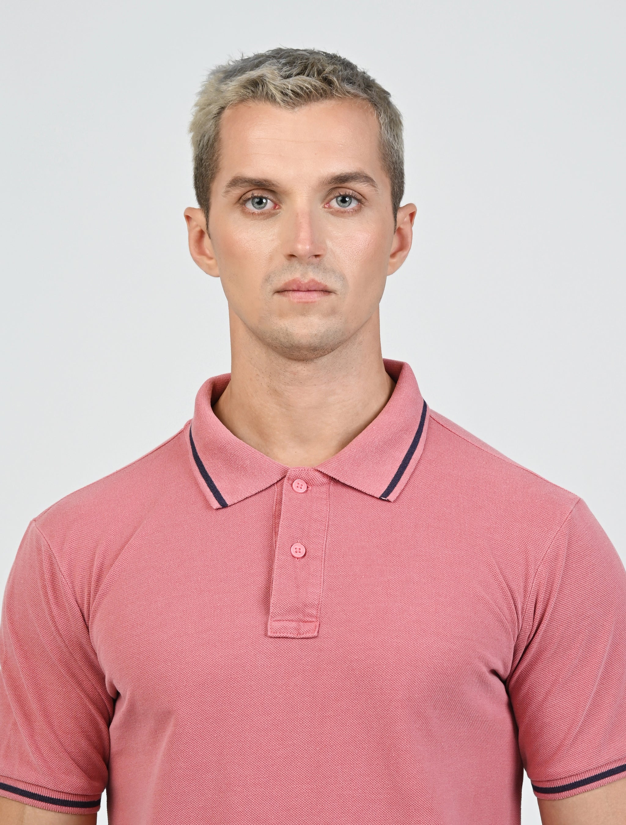 Close-up of the Marshall Menswear Norton Blush Red men's polo shirt highlighting the  pique fabric, contrast navy tipping, classic polo collar and two-button placket.