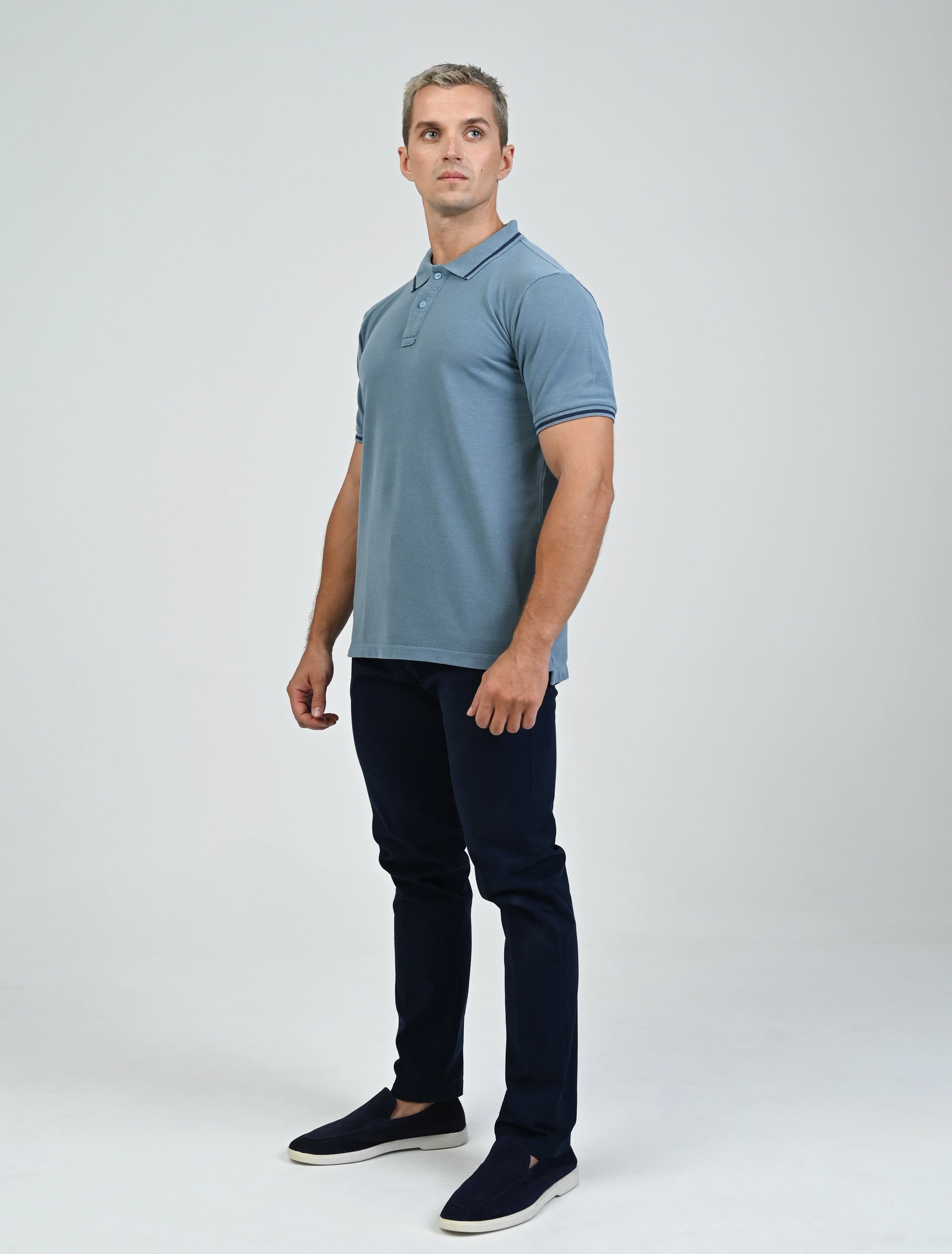 Full-length view of a model wearing the Marshall Menswear Saville Air Force Blue men's polo shirt with contrast blue tipping, navy chinos and black loafers for an elevated smart casual outfit.